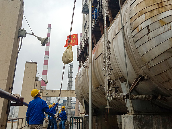 5月10日中午，在动力车间三期工艺除氧器地面，党员突击队队员用滑轮往工艺除氧器平台运送钢丝网，用以缠绕新填料.jpg